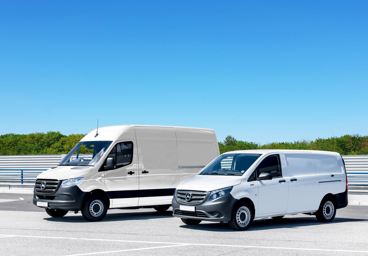 Home Two white delivery vans parked in a spacious parking lot under a clear blue sky.