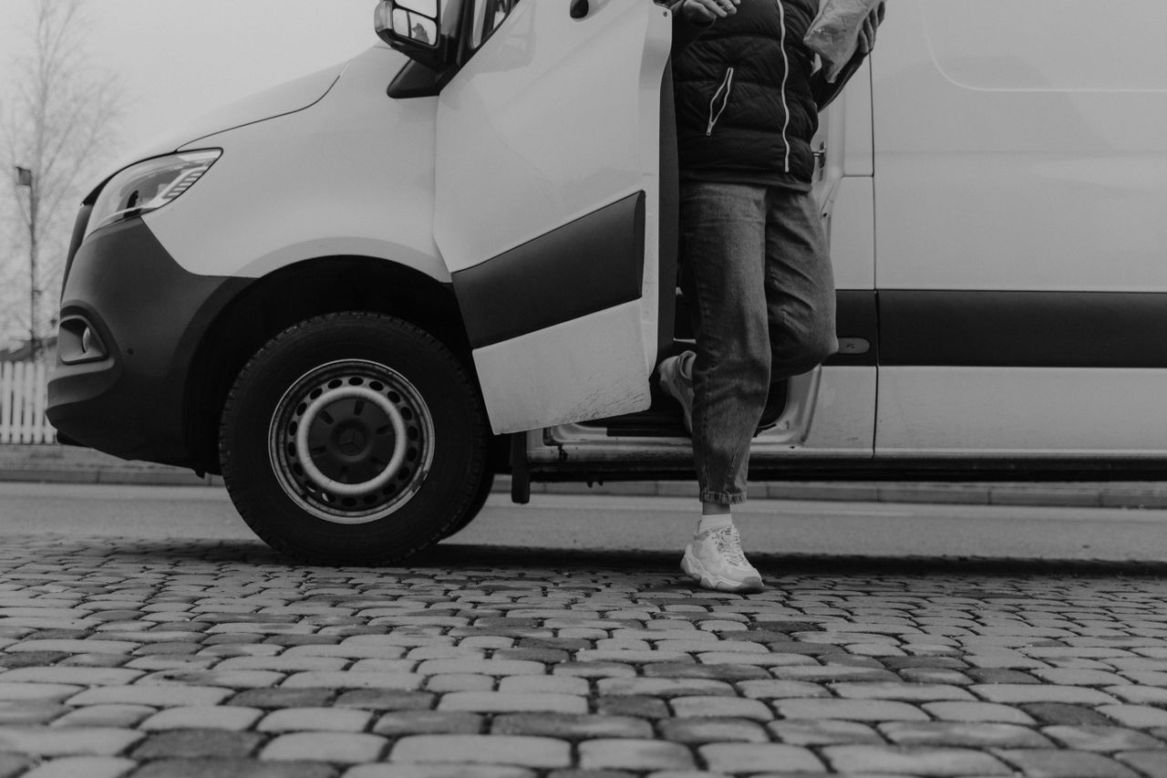 Mastering the First Impression: Your intriguing post title goes here Monochrome image of a person stepping out of a van onto cobblestone pavement.